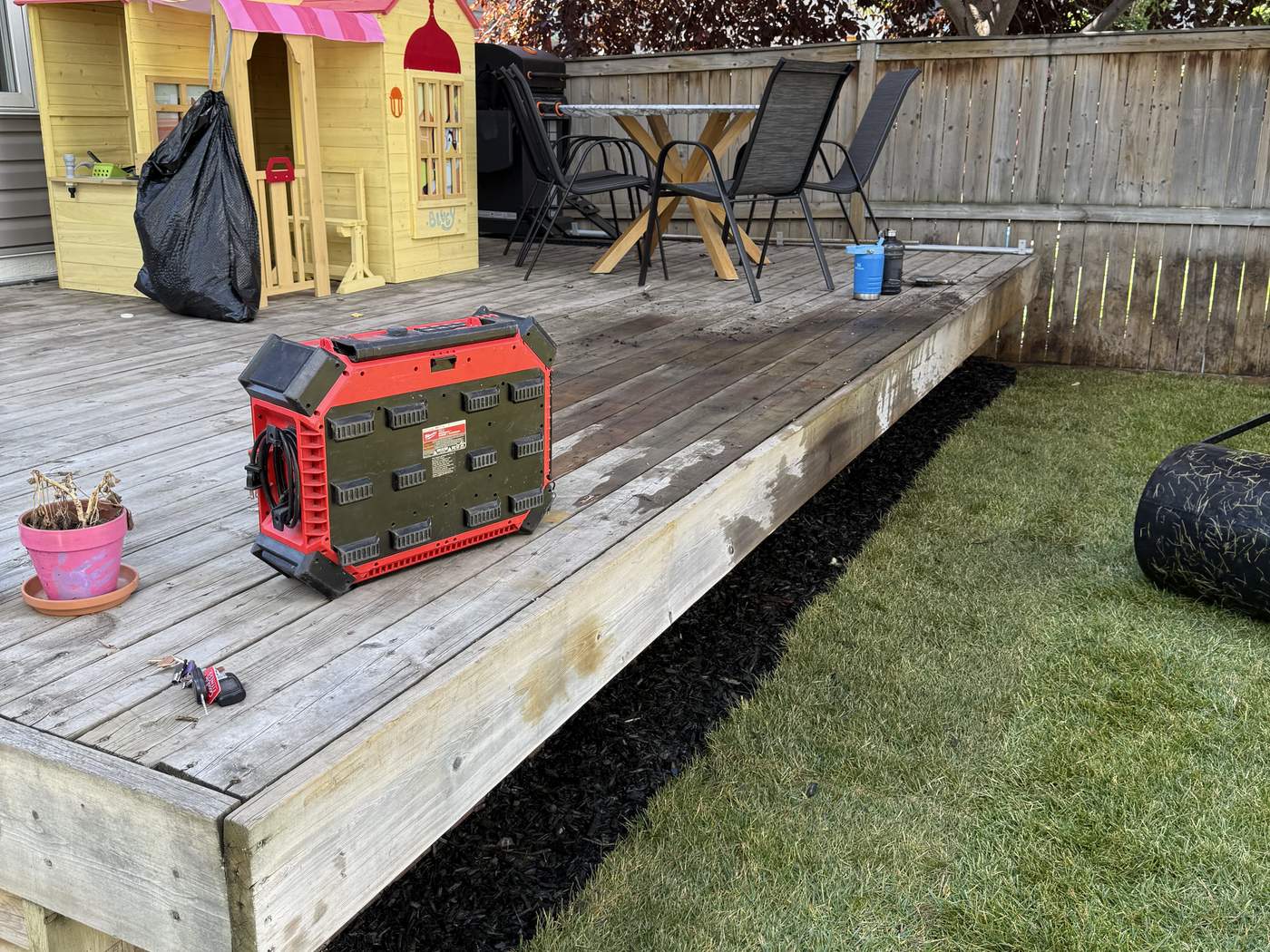 The same deck in front of new sod, with mulch under the deck lip and the sod roller beside it