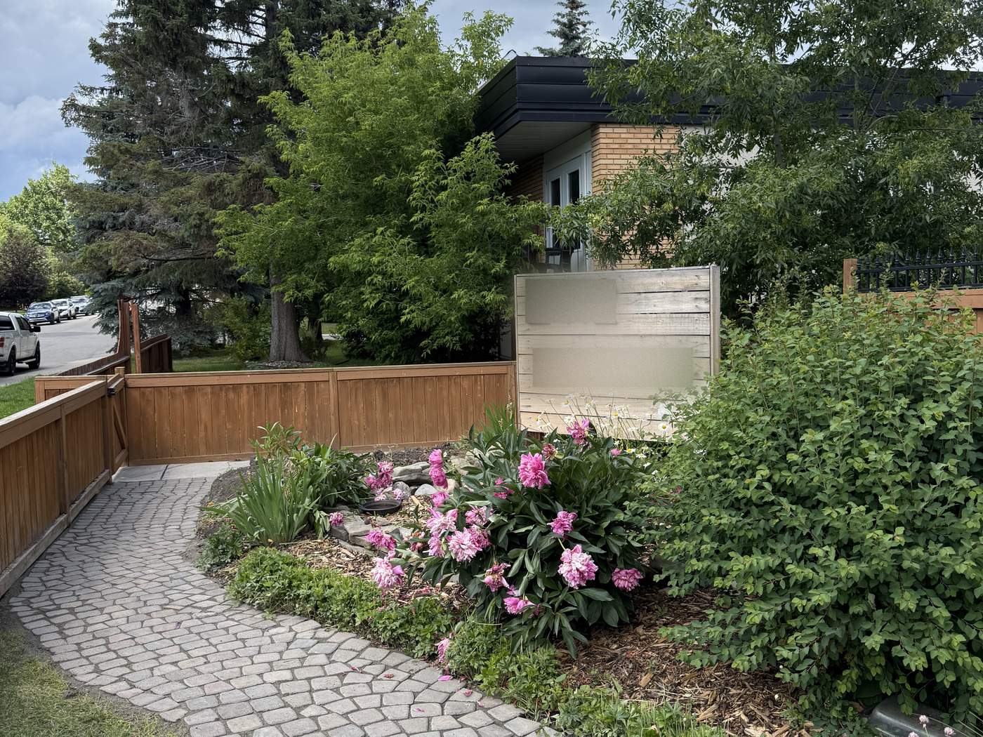 The same front garden after: a curved paver path running from the gate through the lawn and the flower bed