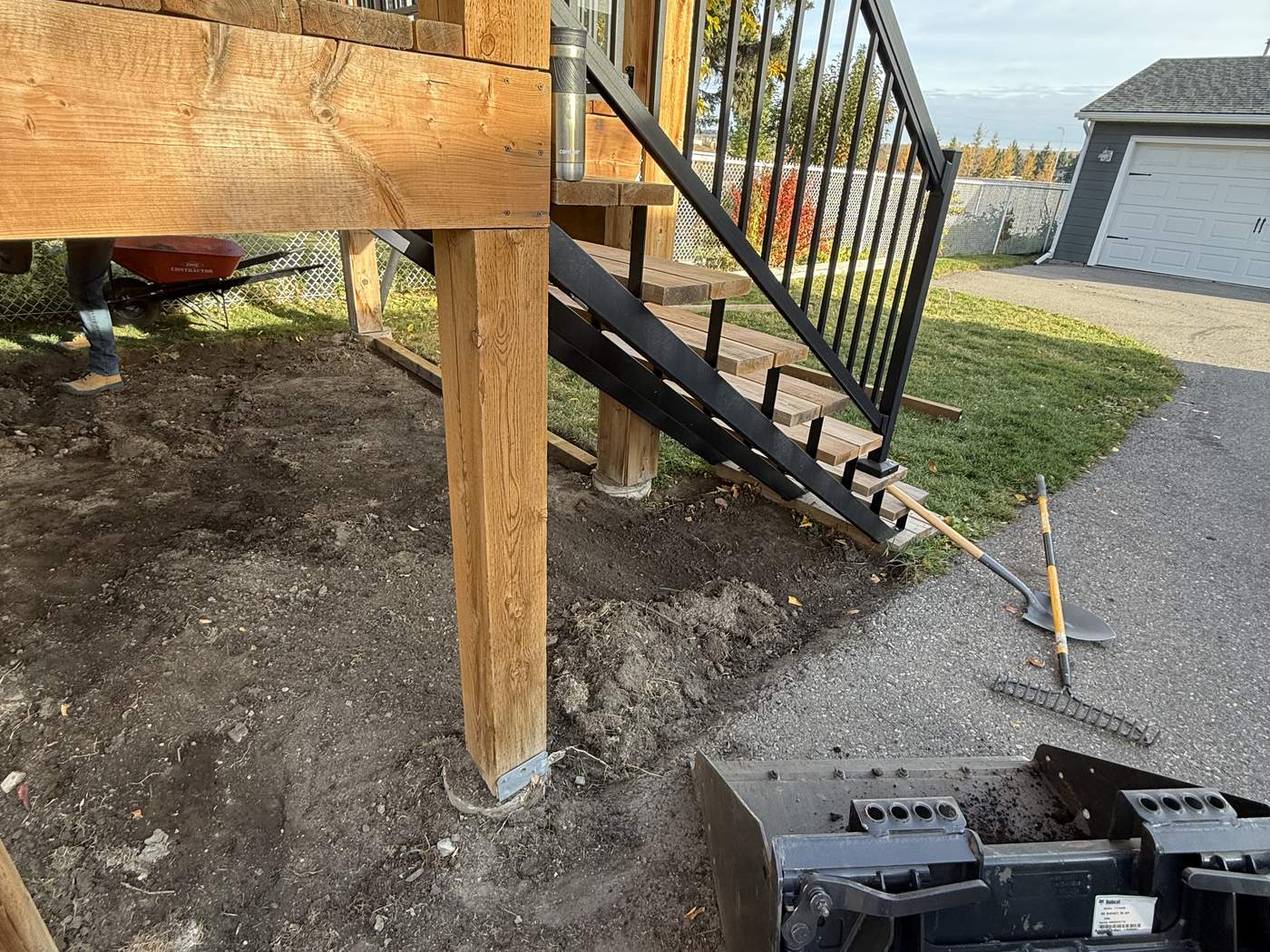 The ground around the deck stairs dug out, the bucket of our Bobcat MT100 in the corner