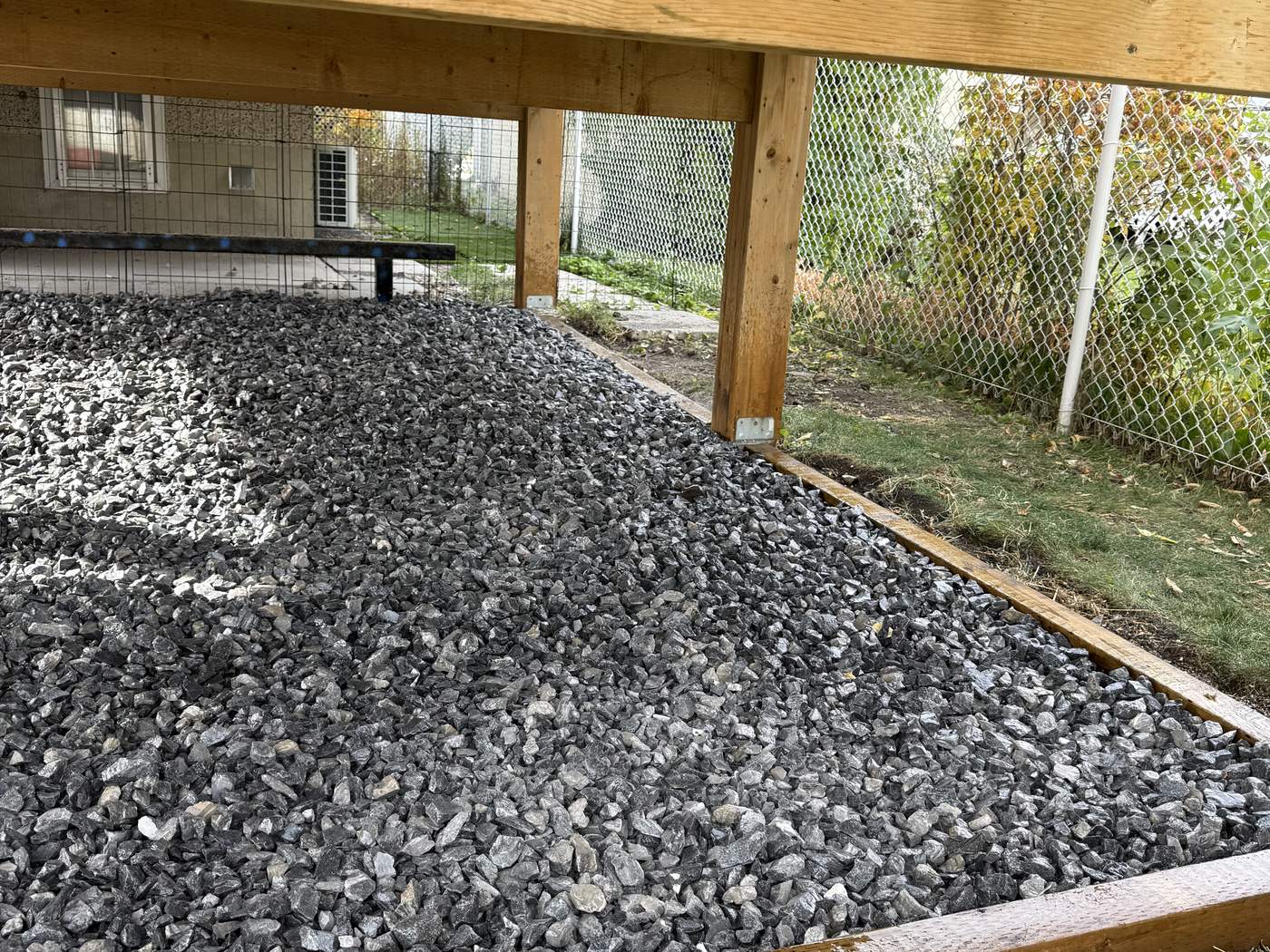 Limestone under the deck held in by pressure-treated wood edging against the lawn