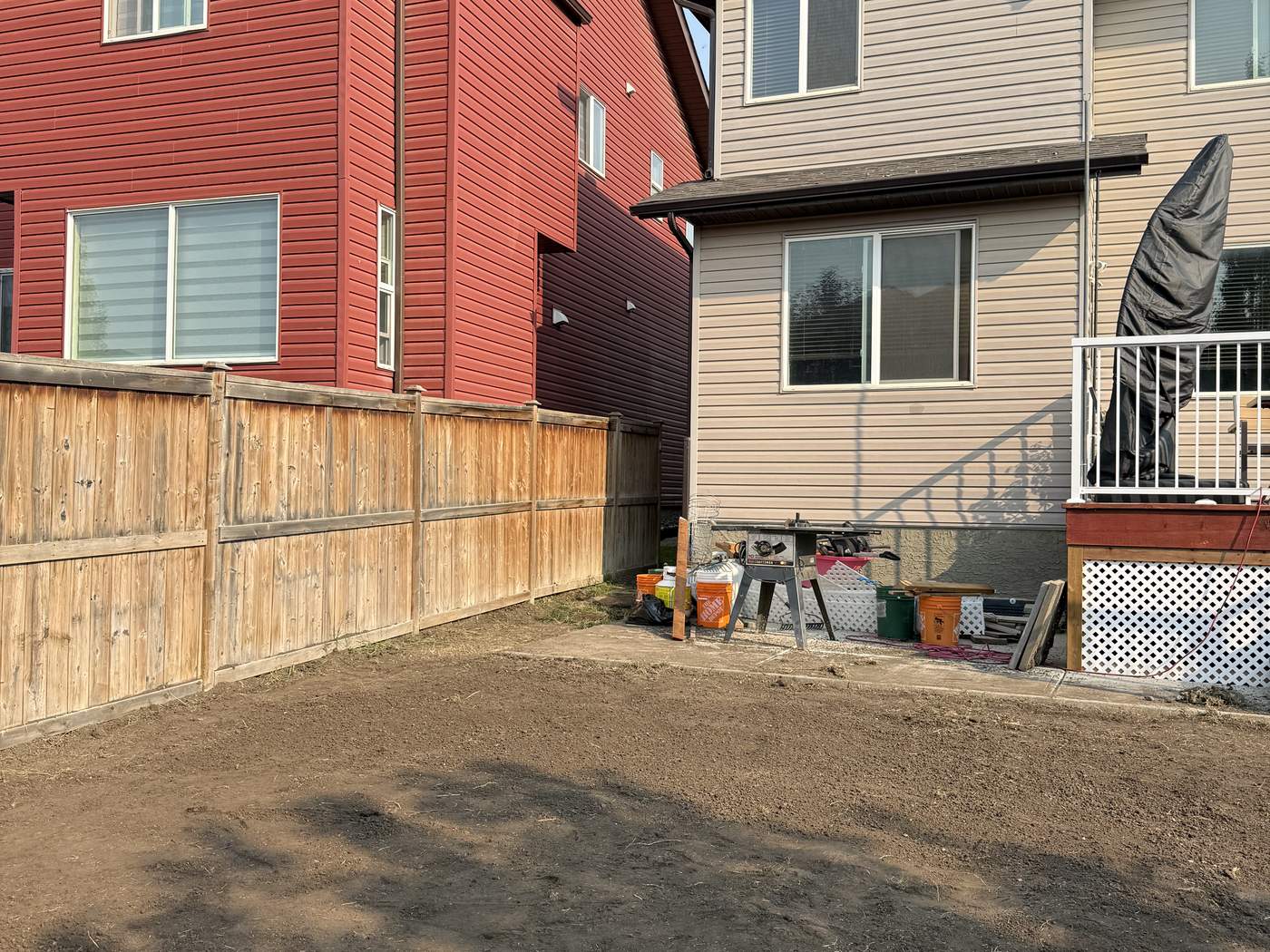 The Sage Hill back yard as bare, graded soil, the back of the house and the neighbour's house behind