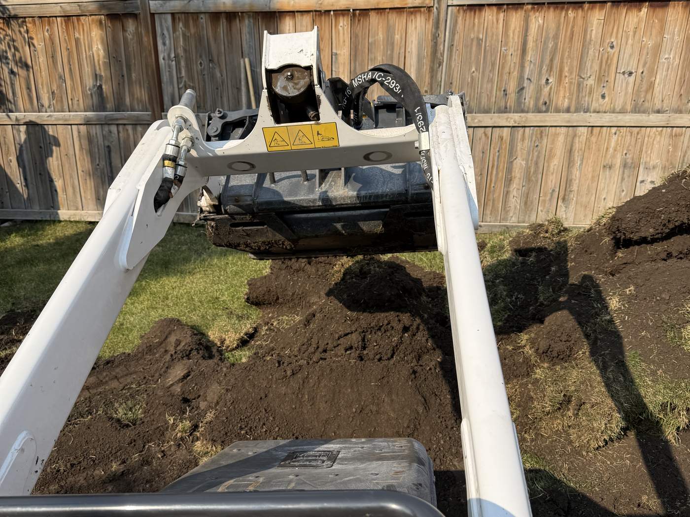 The view from the seat of our Bobcat MT100, its bucket lifting old turf and soil out of the back yard