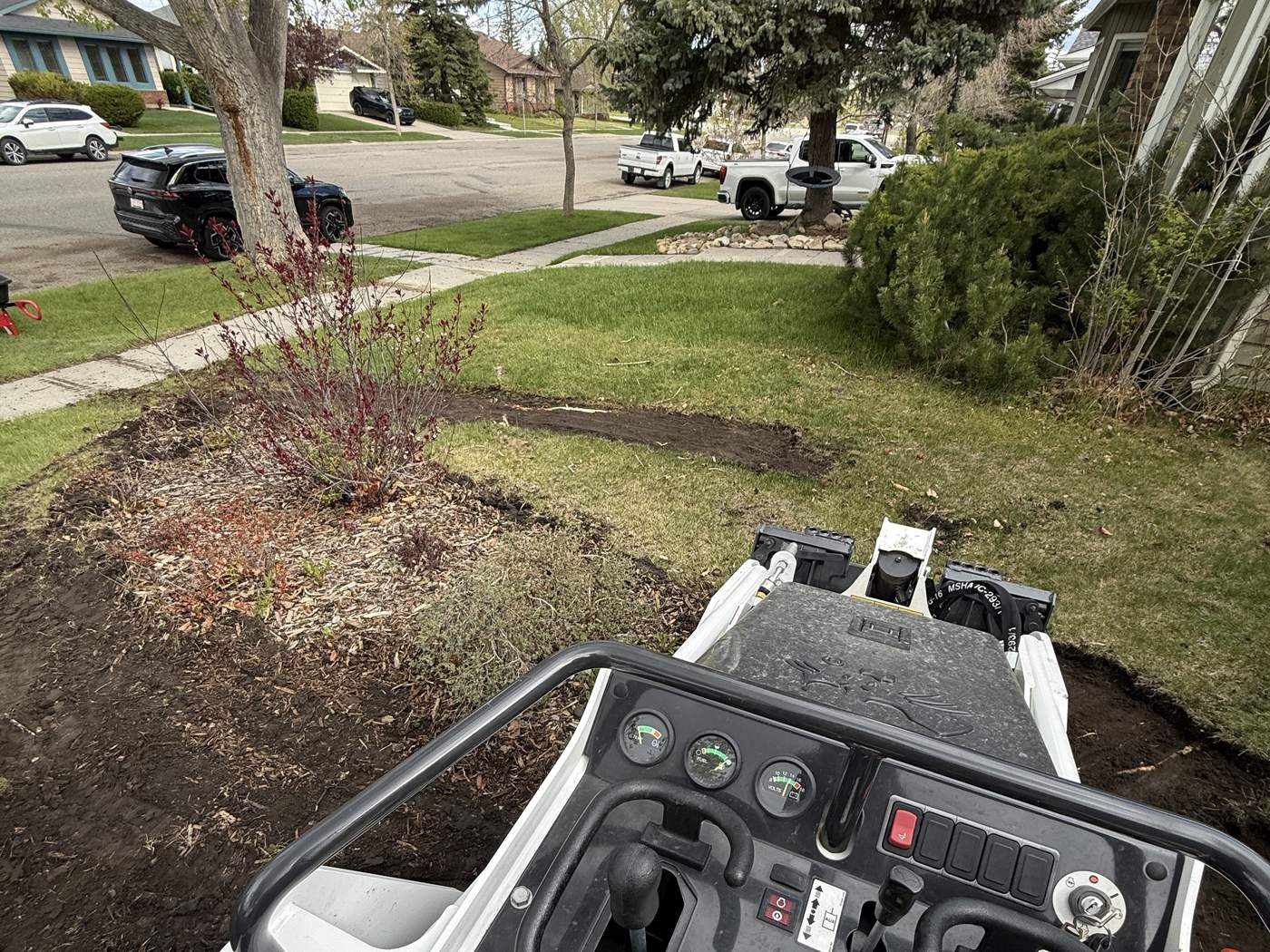 The view from the seat of our Bobcat MT100 as it strips the old front lawn, the street and trees beyond