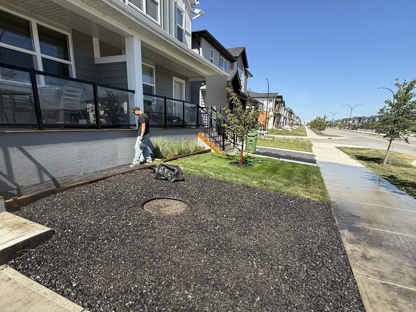 A front bed of dark Rundle rock along the porch, wood edging against the new sod and a young tree in its bed