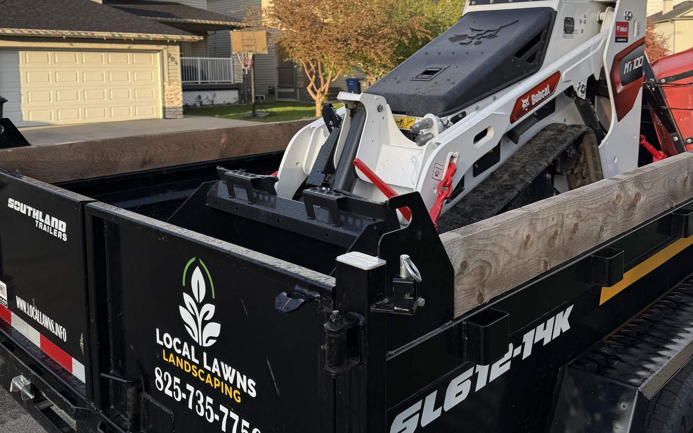 Local Lawns Bobcat MT100 track loader strapped onto the branded Southland dump trailer with its bucket stowed in the box