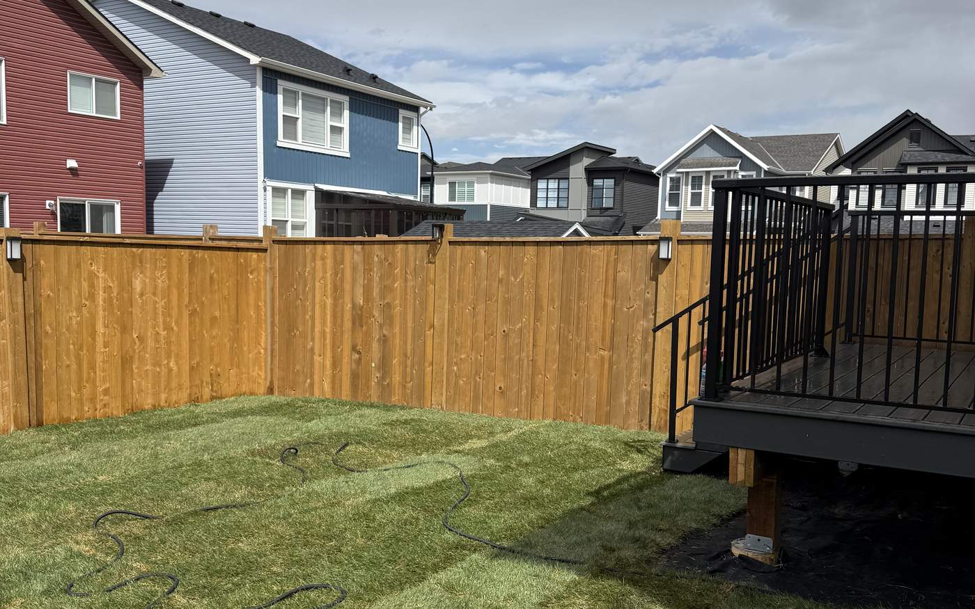 New pressure-treated fence installed straight down the property line in Calgary