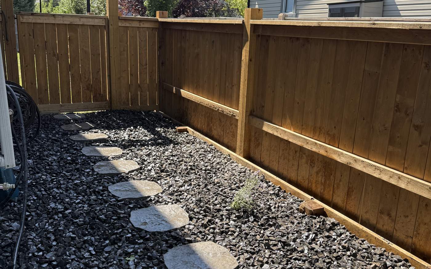 Finished decorative rock bed in Calgary with commercial filter fabric and clean steel edging